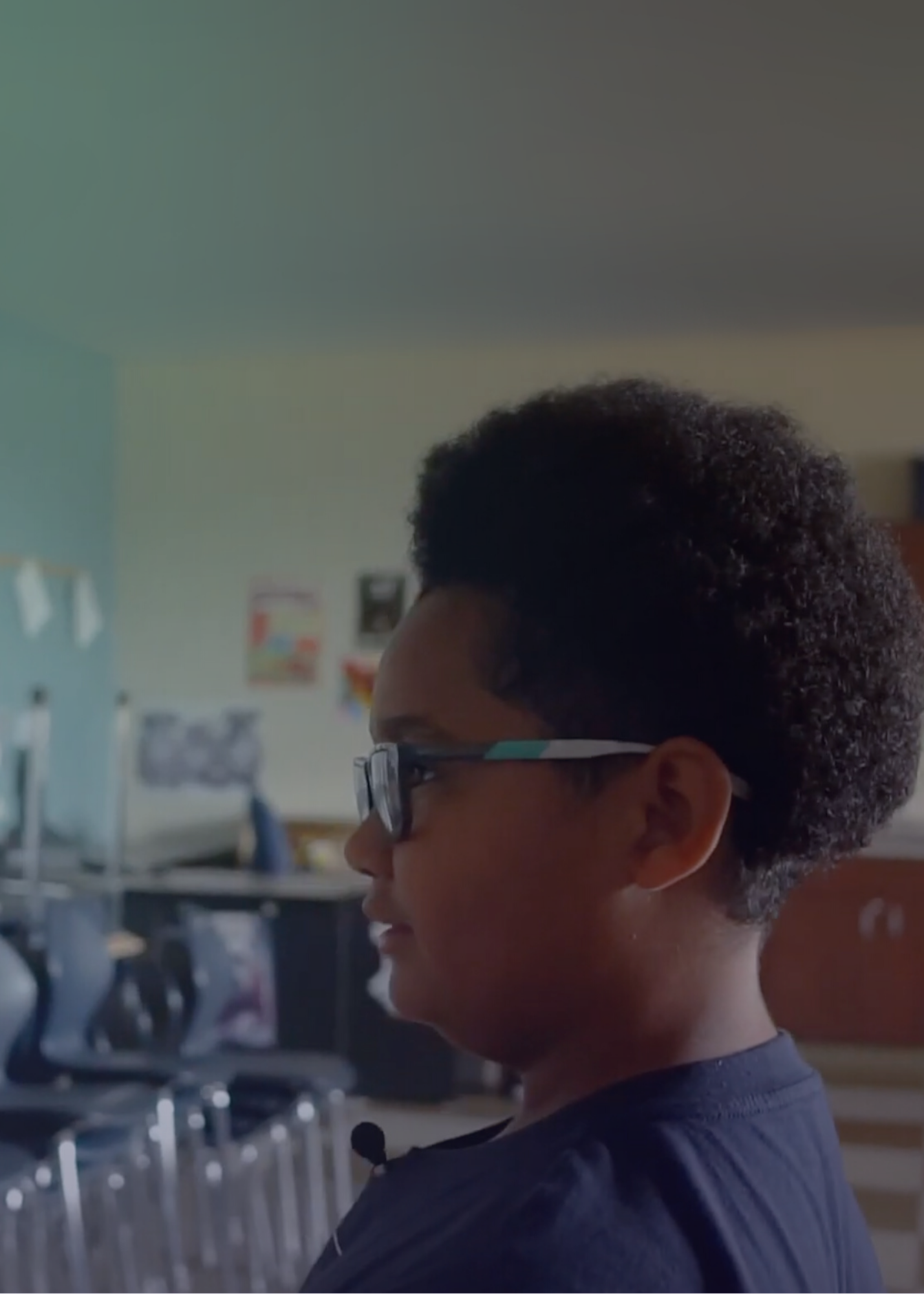 Student standing in empty classroom looking off camera. Student standing in empty classroom looking off camera.