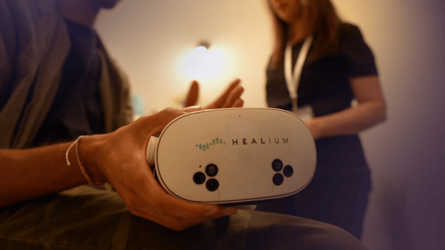 A man holds the Healium goggles as he speaks to a clinician.